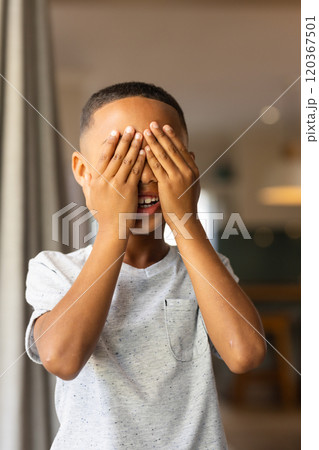 Playing peekaboo, boy covering eyes with hands and smiling indoors 120367501