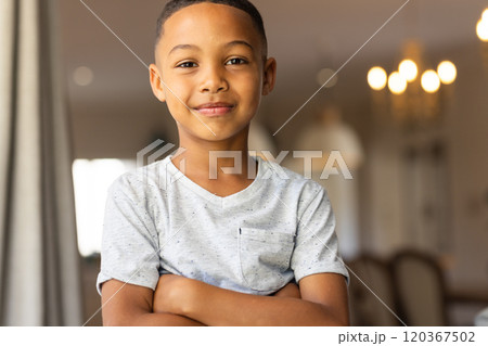 Smiling boy standing with arms crossed in living room, feeling confident Smiling boy standing with arms crossed in living room, feeling confident 120367502