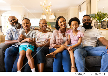Sitting on couch, multigenerational family smiling and enjoying quality time at home 120367551