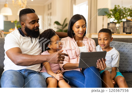 Family sitting on couch, using tablet together, enjoying quality time at home 120367556