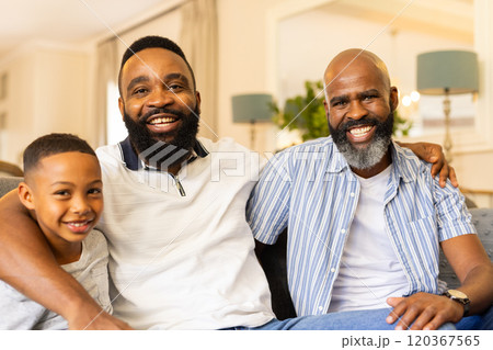 Smiling family of three generations sitting together on couch at home 120367565