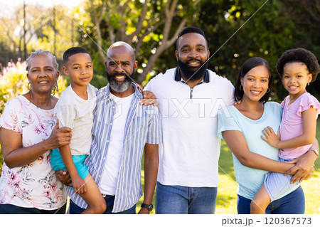 Standing together and smiling, multi-generational family in sunny garden outdoors 120367573