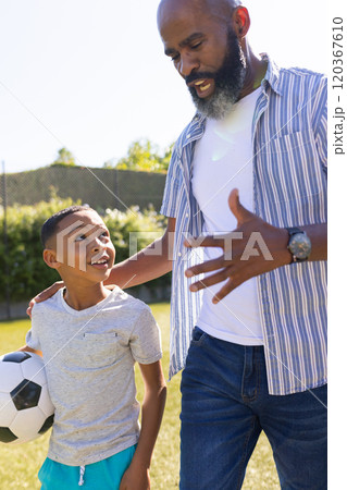 Grandfather and grandson bonding, holding soccer ball and talking outdoors Grandfather and grandson bonding, holding soccer ball and talking outdoors 120367610