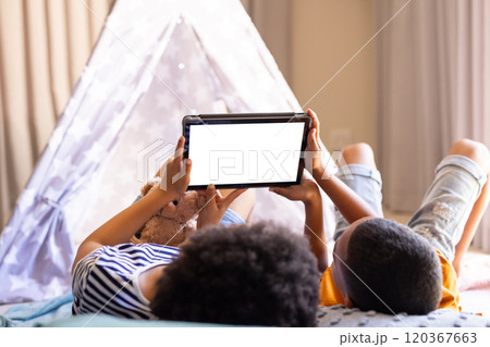 brother and sister lying on bed using tablet, enjoying leisure time at home, copy space, in teepee brother and sister lying on bed using tablet, enjoying leisure time at home, copy space, in teepee 120367663