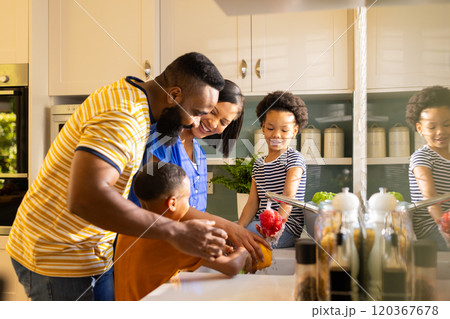 Washing vegetables in kitchen, family enjoying time together, smiling and bonding Washing vegetables in kitchen, family enjoying time together, smiling and bonding 120367678
