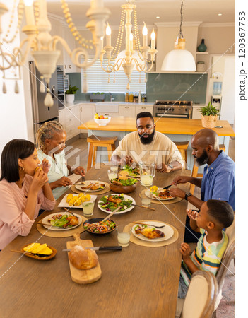 multigenerational family enjoying meal together, sharing food and conversation at dining table multigenerational family enjoying meal together, sharing food and conversation at dining table 120367753