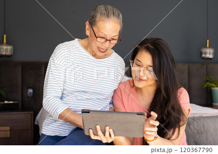 Using tablet,  asian grandmother and granddaughter enjoying time together indoors 120367790