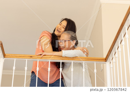 Laughing together, asian grandmother and granddaughter hugging on balcony railing 120367842