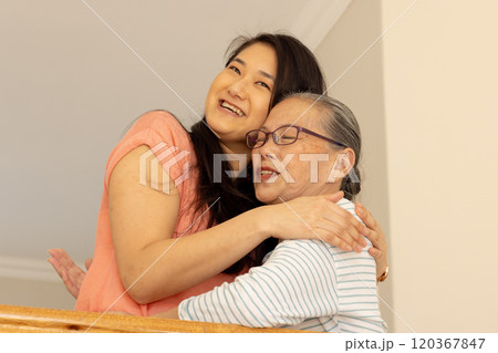 Hugging and smiling, asian grandmother and granddaughter sharing warm moment at home 120367847