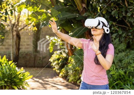 Using VR headset, Asian woman interacting with virtual environment outside 120367854