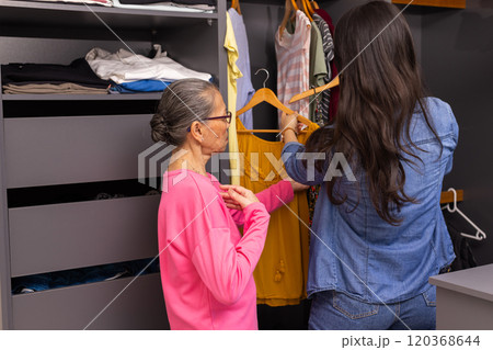 Choosing clothes, granddaughter helping asian grandmother in front of wardrobe at home Choosing clothes, granddaughter helping asian grandmother in front of wardrobe at home 120368644