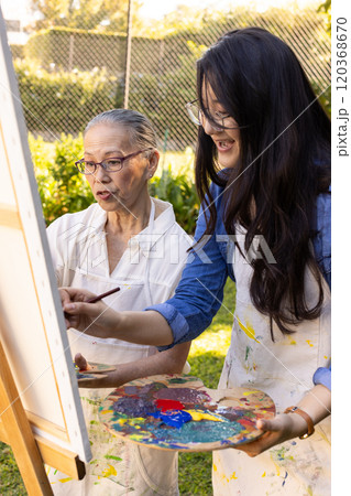 Painting on canvas, Asian granddaughter and grandmother enjoying outdoor art activity together Painting on canvas, Asian granddaughter and grandmother enjoying outdoor art activity together 120368670