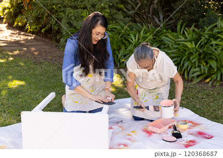 Painting furniture outdoors, Asian granddaughter and grandmother working together on DIY project Painting furniture outdoors, Asian granddaughter and grandmother working together on DIY project 120368687