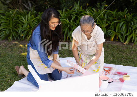 Painting wooden blocks, asian grandmother and gradndaughter enjoying outdoor creative activity toget Painting wooden blocks, asian grandmother and gradndaughter enjoying outdoor creative activity toget 120368709