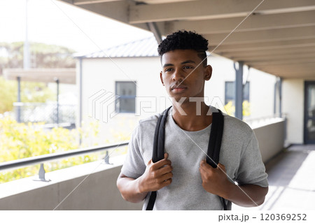 Standing outside school building, teenage boy with backpack looking thoughtful Standing outside school building, teenage boy with backpack looking thoughtful 120369252