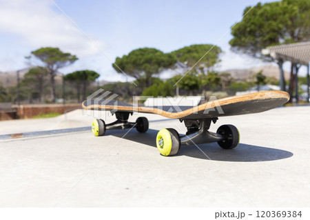 Skateboard resting on concrete surface at outdoor skate park on sunny day 120369384
