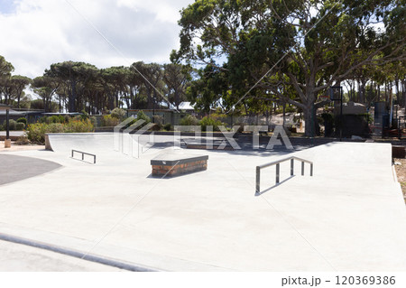 Outdoors, Empty skate park with ramps and rails surrounded by trees and greenery Outdoors, Empty skate park with ramps and rails surrounded by trees and greenery 120369386