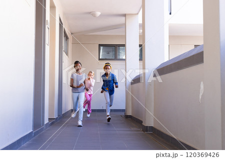 Running in school hallway, three multiracial girls enjoying time together Running in school hallway, three multiracial girls enjoying time together 120369426