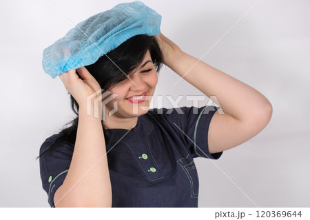 A young smiling nurse puts a medical cap on her hair 120369644
