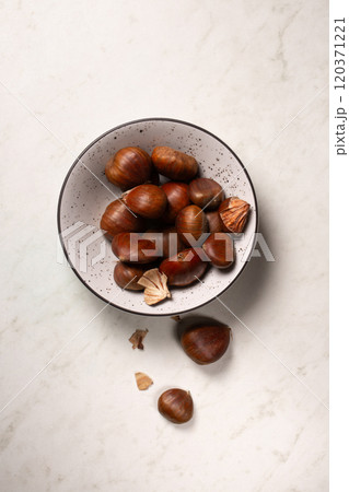 Delicious edible chestnuts in a small bowl on a white table 120371221