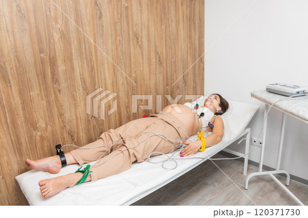 Pregnant woman undergoing ECG test with electrodes attached to limbs and chest Pregnant woman undergoing ECG test with electrodes attached to limbs and chest 120371730