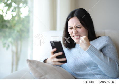 Angry asian woman checking phone at home Angry asian woman checking phone at home 120373161