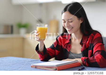 Happy asian student studying drinking orange juice at breakfast 120373188