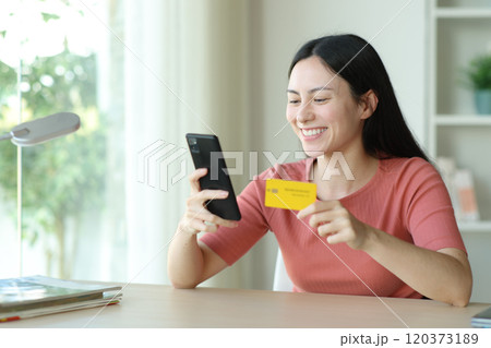 Happy asian woman buying online in a desk 120373189