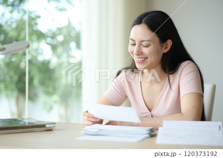 Happy asian woman cheking bill at home Happy asian woman cheking bill at home 120373192