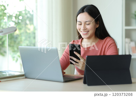 Happy asian woman using multiple devices at home 120373208