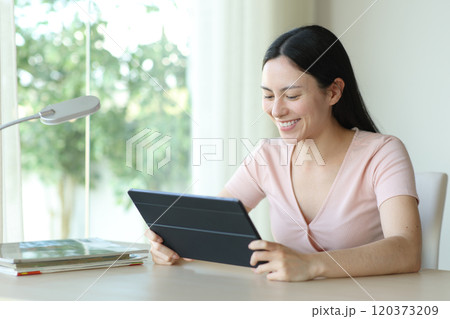 Happy asian woman watching media on tablet at home Happy asian woman watching media on tablet at home 120373209