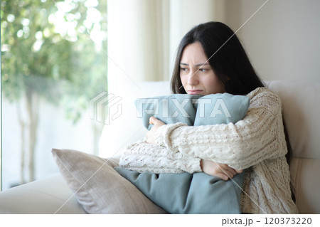Sad asian woman complaining hugging pillow at home 120373220