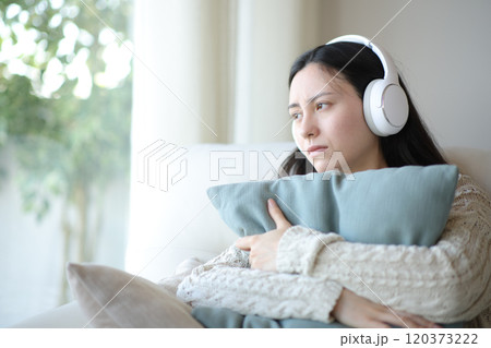 Sad asian woman listening music hugging pillow 120373222