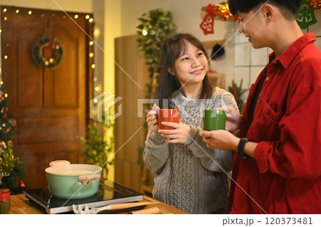 Smiling young couple enjoying a warm drink together in a home kitchen during Christmas 120373481