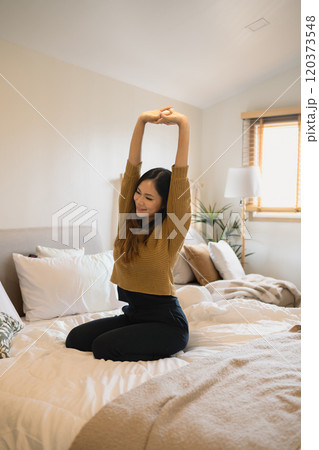 Happy young woman stretching n a comfortable bed for relaxing morning start Happy young woman stretching n a comfortable bed for relaxing morning start 120373548