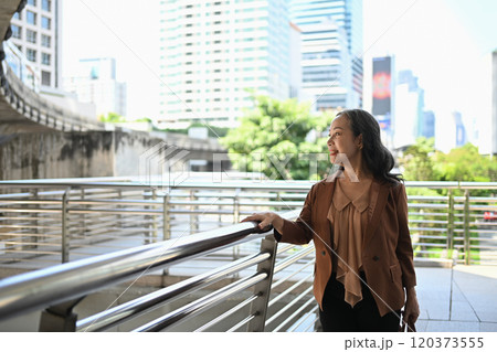 Portrait of elegant mature businesswoman standing in the city and looking upwards Portrait of elegant mature businesswoman standing in the city and looking upwards 120373555