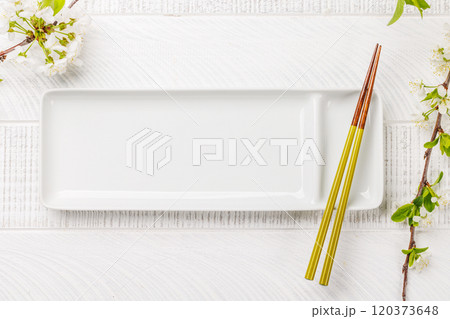 Table adorned with cherry blossom branch and chopsticks, epitomizing Japanese food culture 120373648