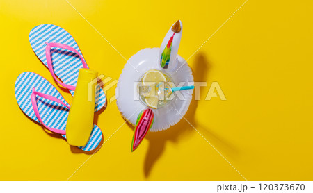 A vibrant summer vacation scene with flip flops, and a floating flamingo with cocktail 120373670