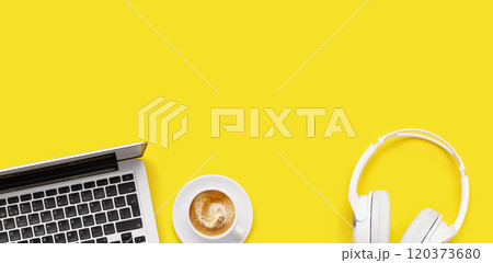 Laptop, headphones, and coffee cup arranged on a yellow background 120373680