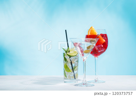 A variety of cocktails arranged on a table against a light blue background 120373757