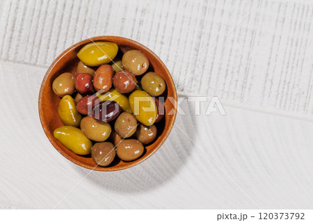 An assortment of various olives presented in a bowl, showcasing different colors, textures, and flavors An assortment of various olives presented in a bowl, showcasing different colors, textures, and flavors 120373792