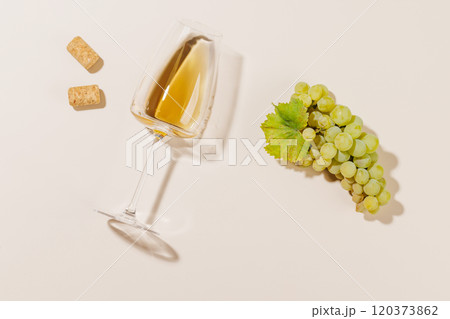 Wine glass alongside grapes and several corks 120373862