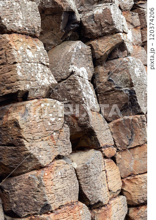 Detailed view of basalt columns at Giant Causeway with worn edges cracks and lichen patterns 120374206