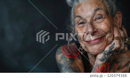Joyful portrait of a senior woman with silver hair and colorful tattoos, showcasing authentic aging with style. Natural lighting highlights her genuine smile and artistic body art against background 120374388