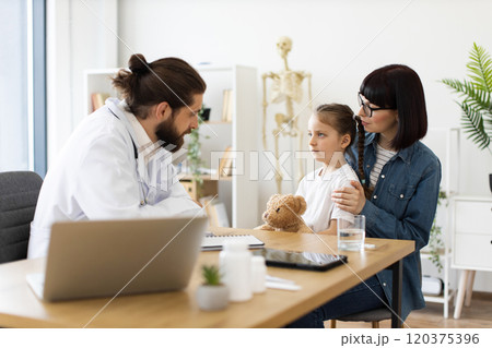 Doctor consulting young patient with parent in modern clinic 120375396