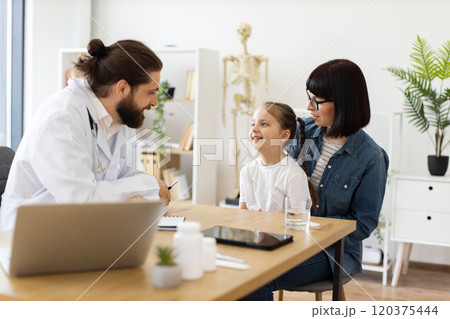 Doctor consults young girl and mother in modern clinic 120375444