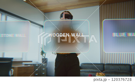 Female designer in virtual reality headset uses interior design app to decorate office workspace 120376728