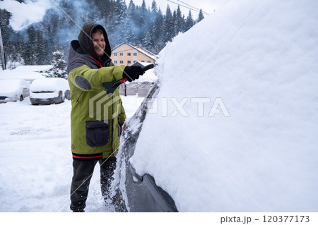 Person Clearing Snow from Car in Winter Landscape 120377173