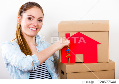 Woman moving in with boxes and paper house key. 120377388