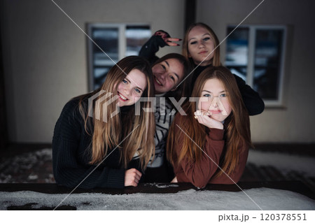 Four happy schoolgirls posing on a snow covered table during a winter photo shoot, having fun together 120378551